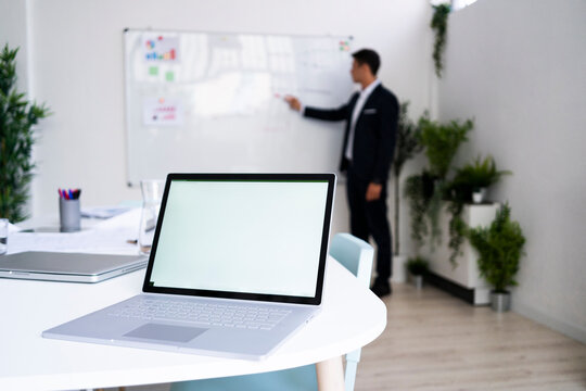 Laptop with blank screen on desk while businessman planning strategy at workplace