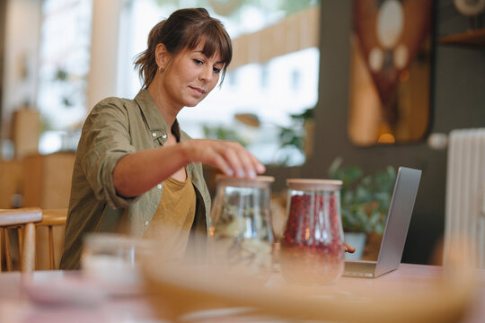 Businesswoman closing glass jars while standing in cafe