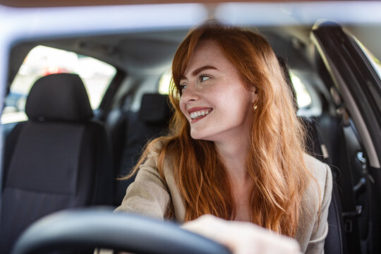 Confident female driver checking blind spots and looking back while reversing a car. Concept for safe driving practices, automotive insurance, driver education, and vehicle security.