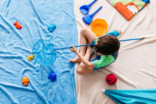 Studio shot of boy fishing with fishing net in water sitting at beach
