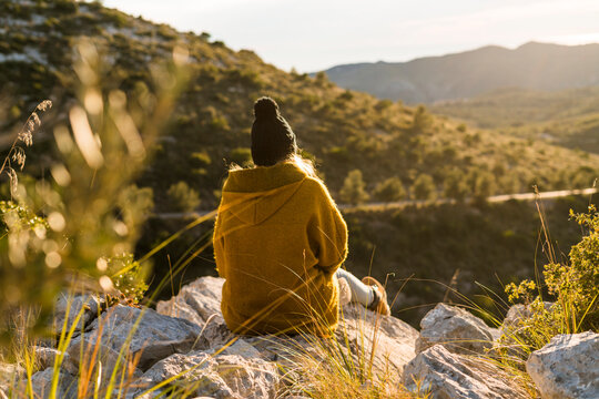 Young woman sitting on rock in nature looking at view