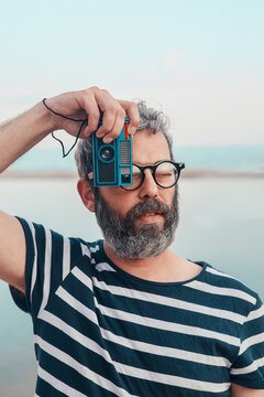 Portrait of bearded man taking photo of viewer with vintage camera