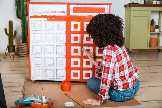Rear view of woman painting furniture with brush at home