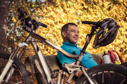 Man with mountainbike having a break sitting on a bench