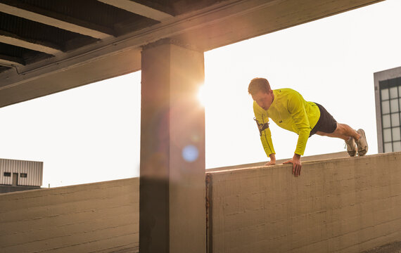 Young athlete exercising push ups on parking level