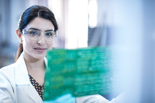 Portrait of smiling female technician holding motherboard