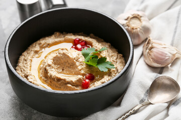 Bowl of tasty baba ghanoush on grey grunge background, closeup
