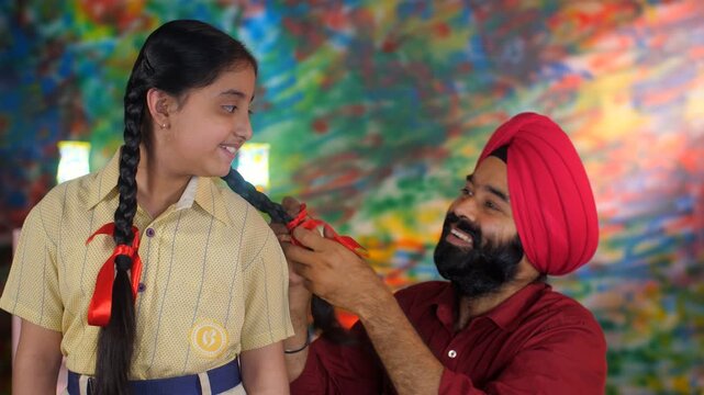 A North Indian Sardar braiding her daughter's hair for school - father-daughter bonding  morning routine. A Sikh Indian man and his adorable daughter in school uniform - a nuclear Punjabi family  s...
