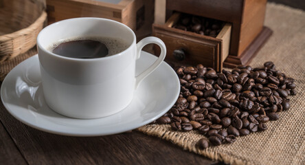 Black coffee in a cup and coffee beans on the table.