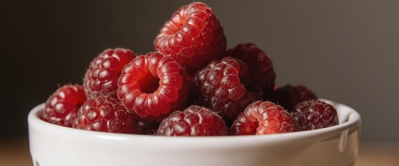 Fresh raspberries piled high in a white bowl, bathed in soft natural light