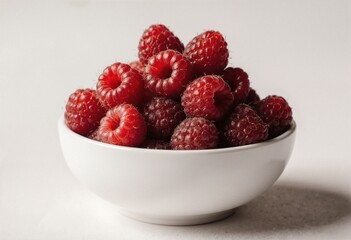 Fresh raspberries piled high in a white bowl, bathed in soft natural light