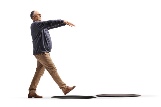 Full length profile shot of a mature man sleepwalking and falling into a hole