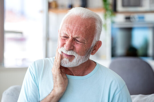 Senior man with toothache touching his face. Elderly male patient suffering from dental pain or sensitive teeth at home. Healthcare and medicine concept. Old person with gingivitis or oral problem.