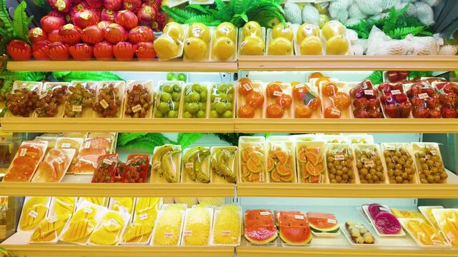 Tropical fruits and sliced produce attractively displayed and pre packaged for sale on multiple refrigerated shelves inside a modern da nang grocery store, highlighting consumer ready convenience