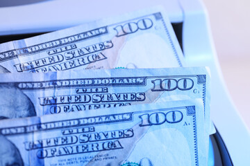 Naklejka premium Modern cash counting machine scanning ultraviolet with dollar banknotes on white background, closeup