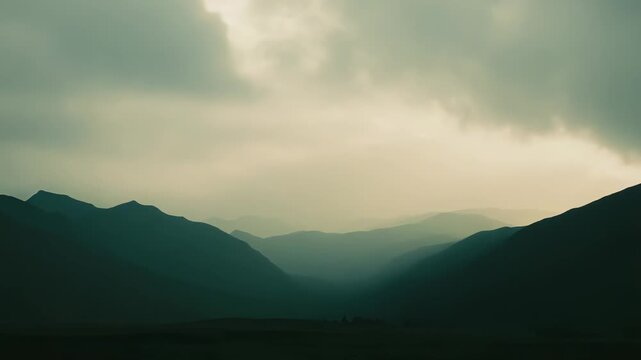 Layered mountain silhouettes fade into mist as heavy clouds part to reveal a single sunbeam, creating a dramatic, ethereal landscape of calm and vastness