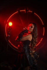 Fototapeta na wymiar Stylish beautiful young woman in black leather corset and boots posing on vintage motorcycle on old garage dark interior background.