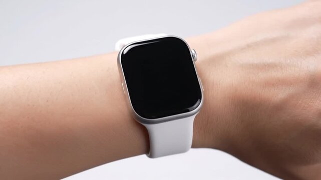 A pristine close-up shot features a modern wearable device on a person's wrist, presenting a sleek design with a silver-toned frame and a clean white strap. The device's dark, blank screen offers gene