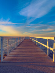 Naklejka premium wooden bridge over the sea, sunset time