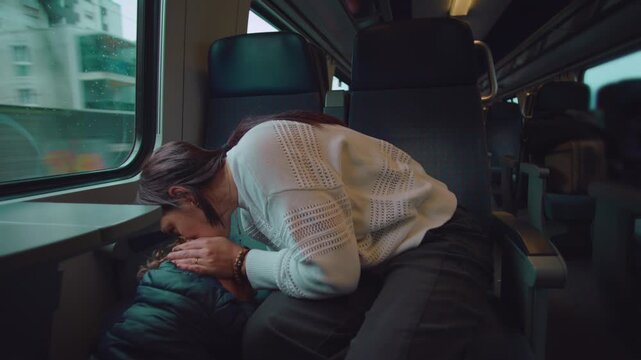 Mother embraces toddler after minor bump on train kissing head to comfort pain conveying protection affection healing care and emotional safety during everyday family commute