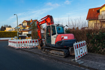 A small excavator sits parked on the side of the road.