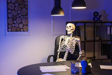 Human skeleton model sitting in office at night