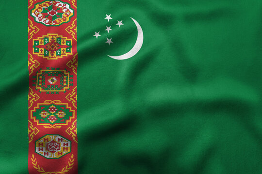 National flag of Turkmenistan featuring a green field with a vertical red stripe containing five carpet guls and a white crescent moon with five stars, representing national heritage.