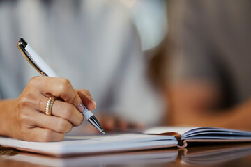 Woman's hand writing in notebook, planning business ideas