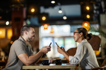 Couple interacting with smartphones on coffee shop date