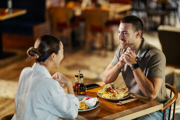 Happy young couple enjoying lunch and conversation in restaurant