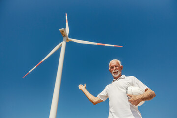 Senior Male Environmentalist Presenting Large White Wind Turbine Clear Blue Sky Renewable Energy