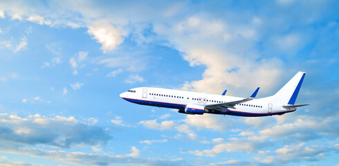 Fototapeta premium Airplane flying in blue sky, air travel background with white commercial airplane in flight in the sunset sky