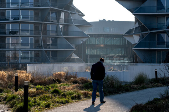 Pedestrian lifestyle on pathway facing modern architecture building showing sustainable urban design in Copenhagen Denmark with warm light and open public space