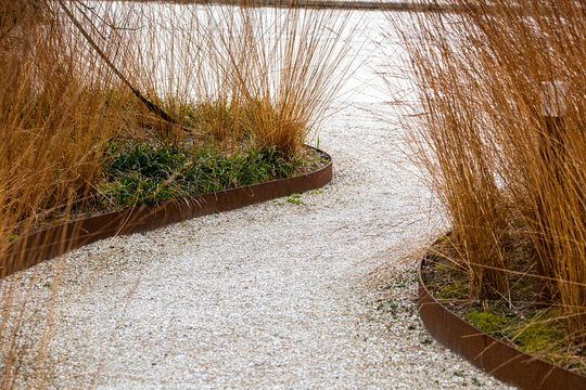 Winding pathway of gravel beside planting and grasses in garden landscaping for sustainable urban Copenhagen Denmark park design with natural textures