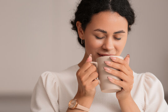 Beautiful young African-American woman with cup of hot coffee at home, closeup