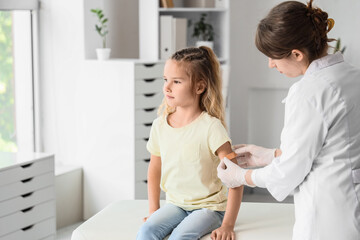 Obraz premium Female doctor applying patch on little girl's arm after vaccination in clinic