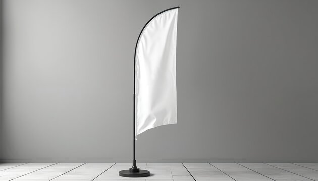 Tall white feather flag stands on round base in studio. Vertical banner is blank for custom ad design. Empty fabric sail on pole against grey wall backdrop. Copy space for text.