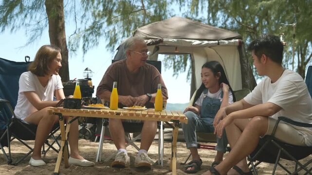 Family camping trip offers beach fun, kids adults relax near tent outdoor, multi generational group enjoys drinks snacks around wooden table fostering joyful connections.