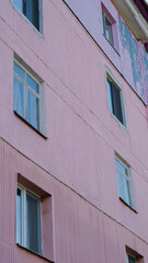 Obraz premium Pink exterior wall of residential building with windows and peeling paint
