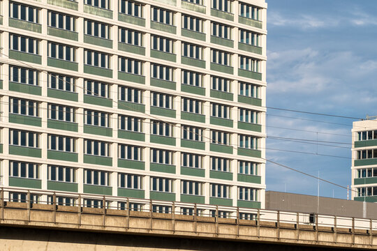Modern urban architecture building facade with windows above bridge and railway under open sky creating strong grid pattern in city view