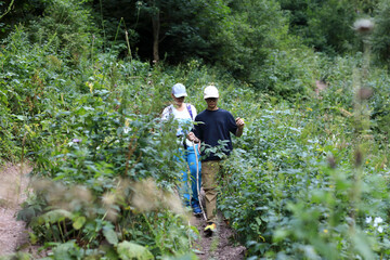 Obraz premium Woman and boy hiking on narrow path surrounded by lush green plants