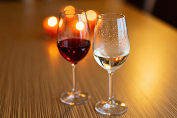 Fototapeta premium Wine Glasses in Harmony: Two elegant wine glasses, one filled with the rich ruby of red wine and the other holding the crisp clarity of white wine, stand side by side on a polished wooden surface.