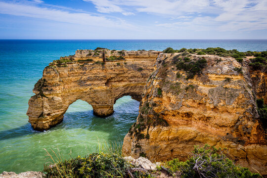View of rugged cliffs, carved by time and tide, stand majestically against the azure sea under a vast sky, creating a breathtaking coastal panorama, Lagoa, Faro, Portugal.