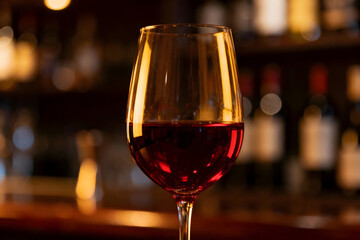 Crimson Wine: A delicate glass filled with a rich crimson wine, its presence against a blurred background of a sophisticated bar, creating a scene of warmth and elegance.