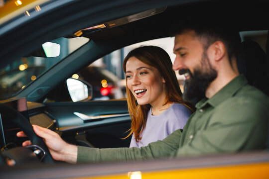 Excited couple exploring dashboard of their new car