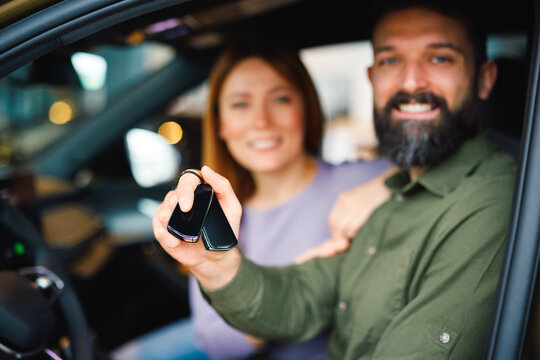 Couple showing car key inside their new vehicle