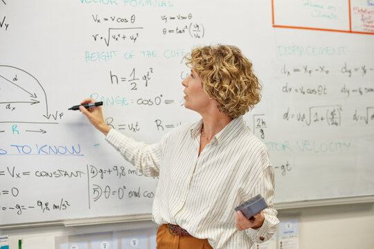 Mature high school teacher explaining physics formulas