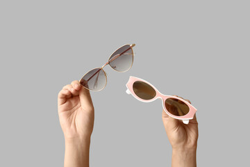 Female hands with different stylish sunglasses on grey background
