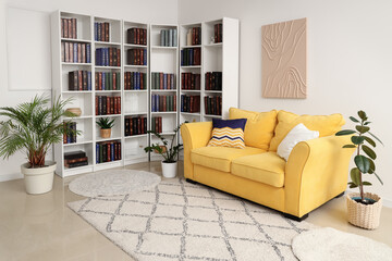 Yellow sofa and bookshelves with many books in light living room © Pixel-Shot