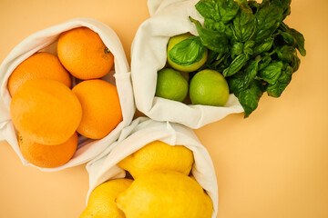Colorful fruits and herbs are arranged in reusable cloth bags on a pastel background, highlighting the importance of eco-friendly grocery shopping and healthy eating habits.